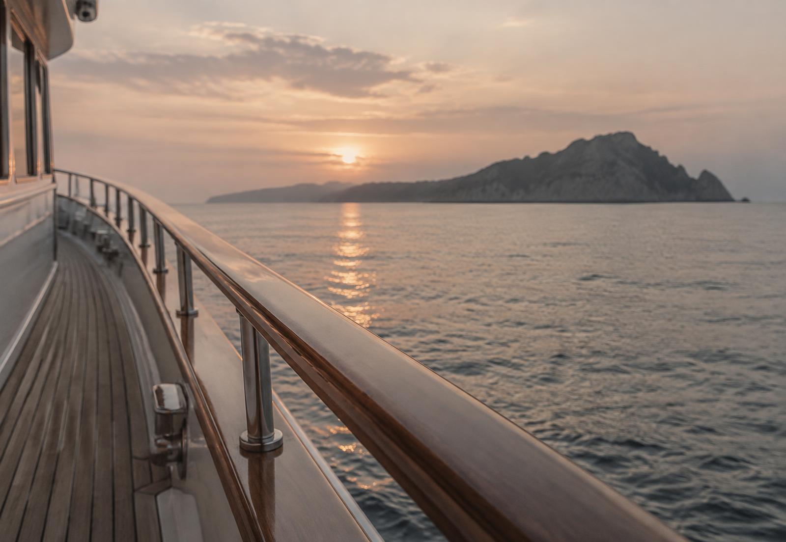The teak deck rail of a small ship at dawn